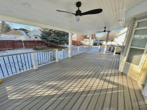 Covered deck with fans and a snowy backyard.
