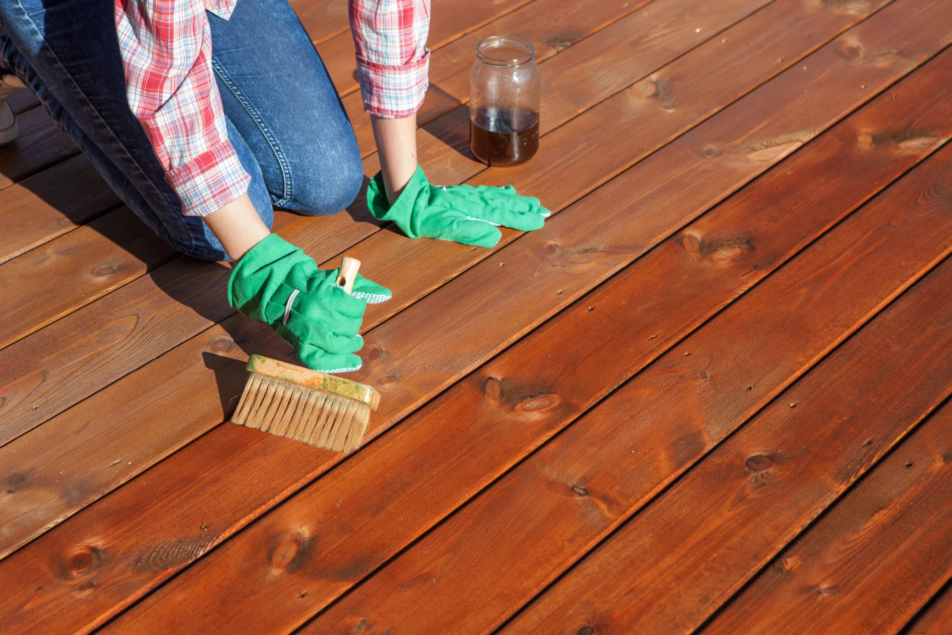 Applying stain to a wooden deck for fall maintenance.